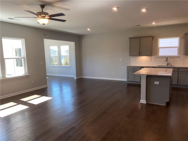 kitchen featuring a sink, visible vents, gray cabinetry, and dark wood-style floors