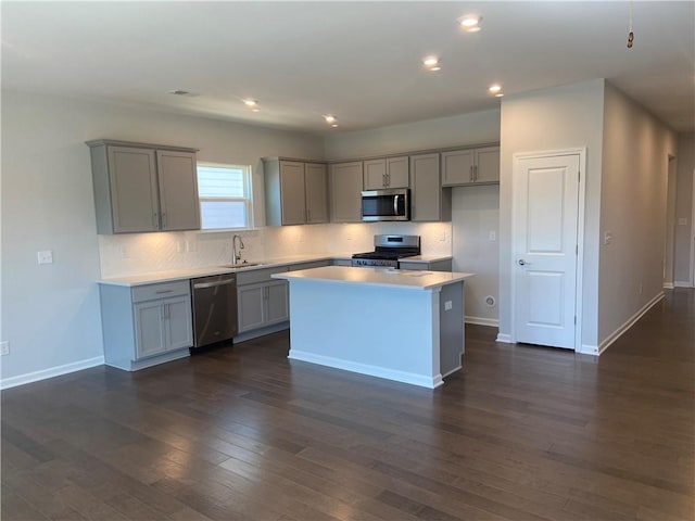 kitchen with dark wood-style flooring, gray cabinets, appliances with stainless steel finishes, and a sink