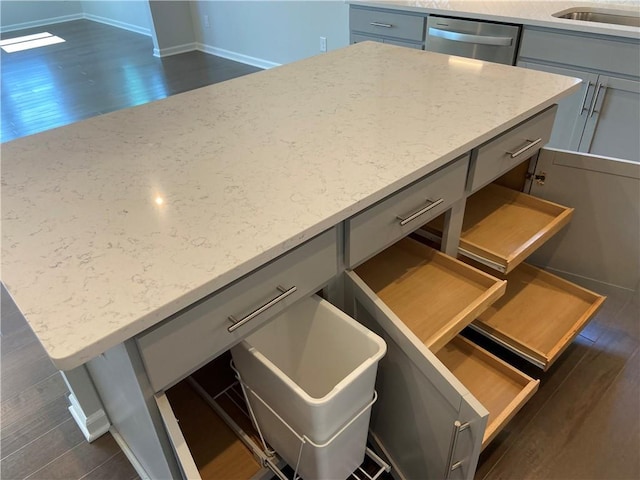 room details with gray cabinetry, light stone counters, a sink, dark wood-style floors, and dishwasher