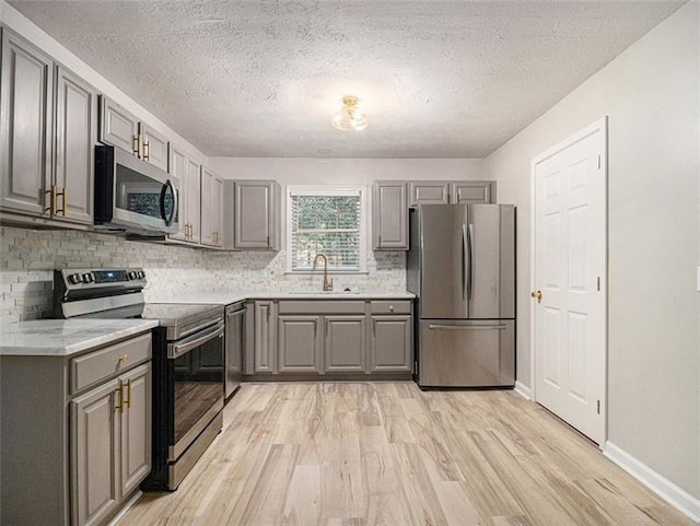 2544 Peyton Woods Trl SW, Atlanta, GA 30311 - kitchen featuring stainless steel appliances, gray cabinets, a sink, light wood-style floors, and tasteful backsplash