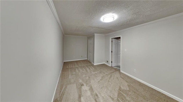 carpeted empty room featuring a textured ceiling, baseboards, and crown molding