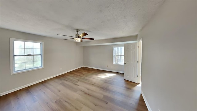 empty room featuring a ceiling fan, a textured ceiling, baseboards, and wood finished floors