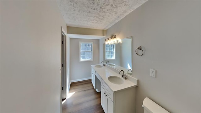 bathroom featuring toilet, a textured ceiling, a sink, and wood finished floors