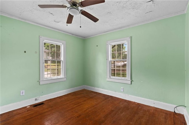 unfurnished room featuring visible vents, crown molding, wood finished floors, and a wealth of natural light