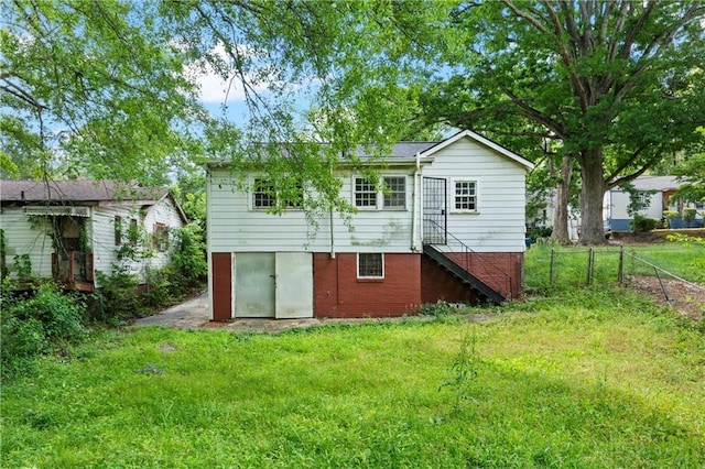 rear view of house with a yard, brick siding, stairway, and fence