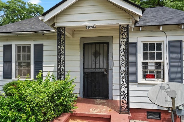 entrance to property with roof with shingles and a porch