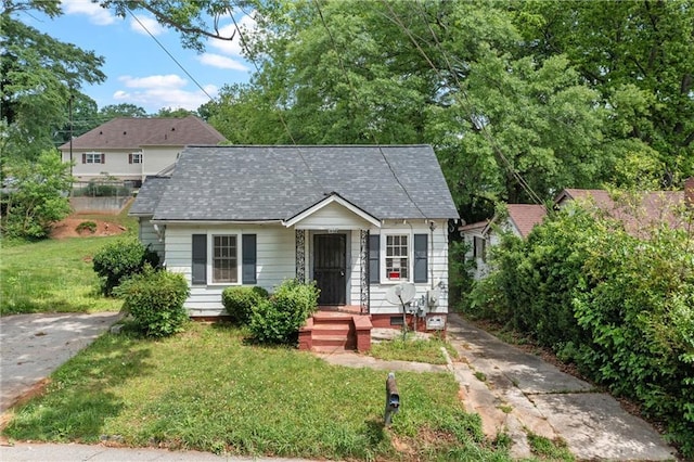 bungalow-style house featuring a front lawn and roof with shingles