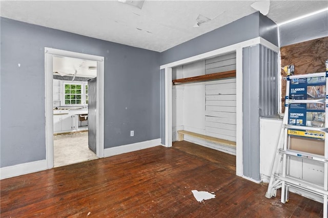 unfurnished bedroom featuring baseboards, wood-type flooring, and a closet