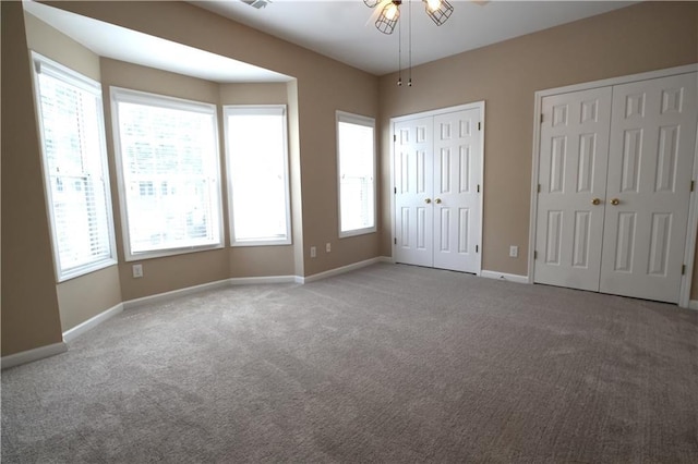 unfurnished bedroom featuring two closets and carpet