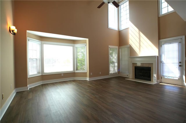 unfurnished living room featuring ceiling fan, dark wood-type flooring, and a towering ceiling