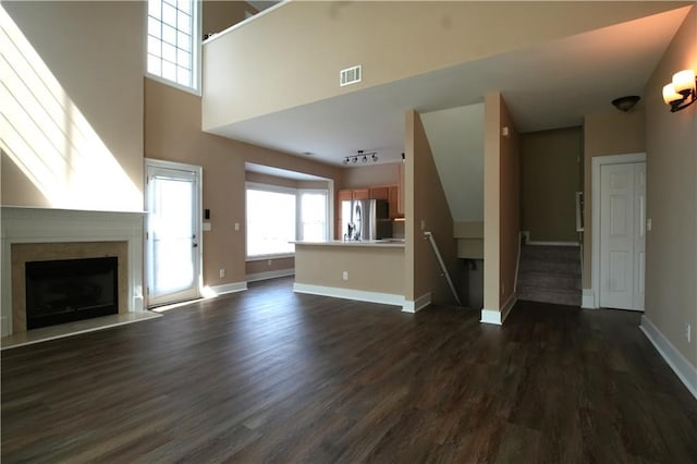 unfurnished living room featuring a high ceiling and dark hardwood / wood-style floors