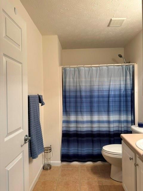 bathroom with curtained shower, vanity, toilet, tile patterned floors, and a textured ceiling