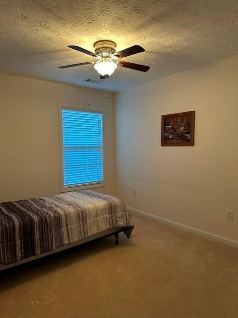 carpeted bedroom with a textured ceiling and ceiling fan