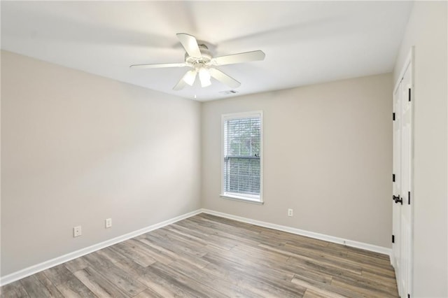 empty room with visible vents, wood finished floors, baseboards, and ceiling fan