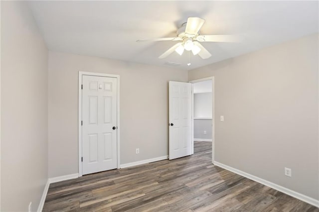 unfurnished bedroom featuring ceiling fan, visible vents, baseboards, and wood finished floors