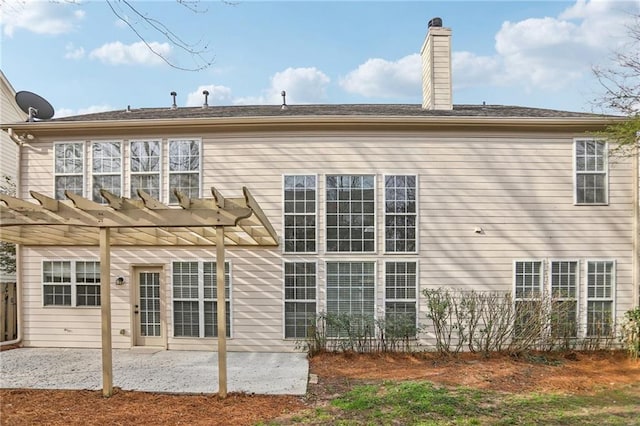 rear view of property featuring a patio, a pergola, and a chimney