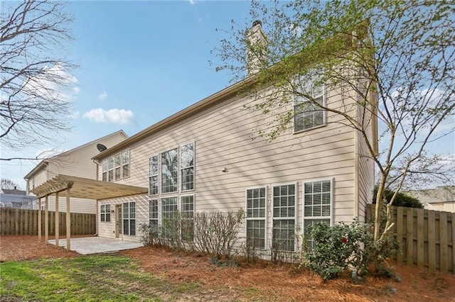 rear view of house with a fenced backyard, a chimney, and a patio area