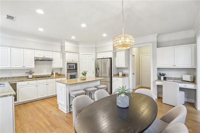 kitchen featuring under cabinet range hood, a kitchen island, light wood-style floors, appliances with stainless steel finishes, and white cabinets