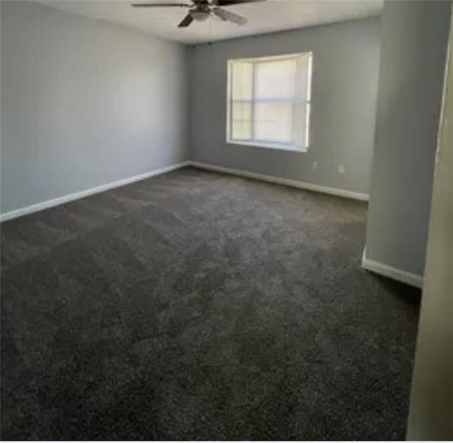 empty room featuring ceiling fan, baseboards, and dark colored carpet