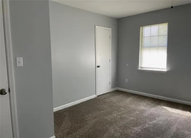 carpeted empty room featuring baseboards