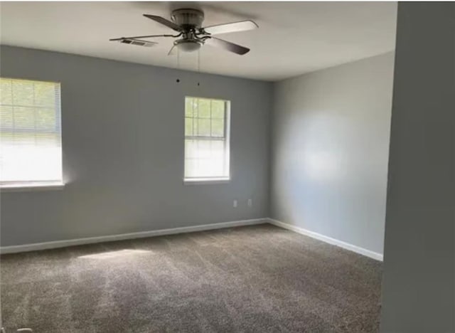 carpeted spare room featuring visible vents, a ceiling fan, and baseboards