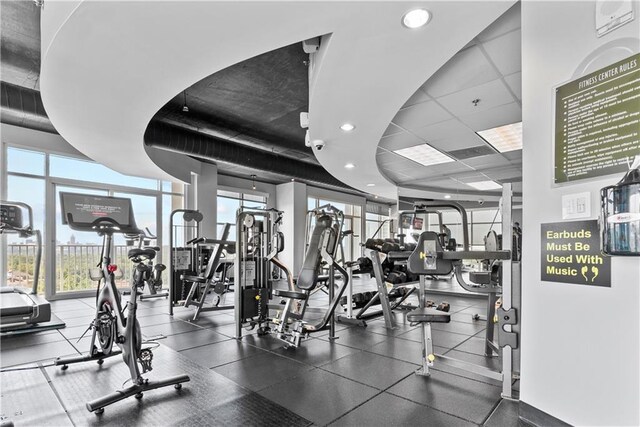 workout area with a paneled ceiling and light hardwood / wood-style flooring