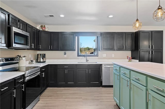 kitchen featuring hanging light fixtures, appliances with stainless steel finishes, sink, and light hardwood / wood-style flooring