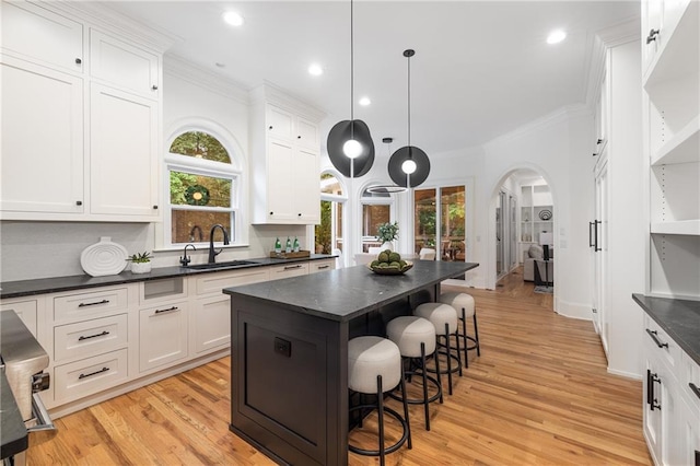 510 Northland Ridge Ct, Sandy Springs, GA 30342 - kitchen featuring ornamental molding, a kitchen breakfast bar, a center island, arched walkways, and light wood-type flooring