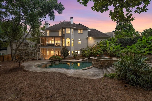 510 Northland Ridge Ct, Sandy Springs, GA 30342 - back of house at dusk with stairway, a chimney, an in-ground hot tub, stucco siding, and an outdoor pool