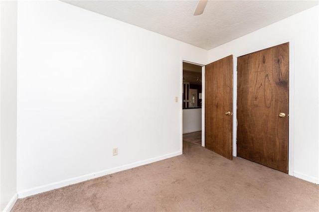 unfurnished bedroom with a closet, light carpet, a textured ceiling, and baseboards