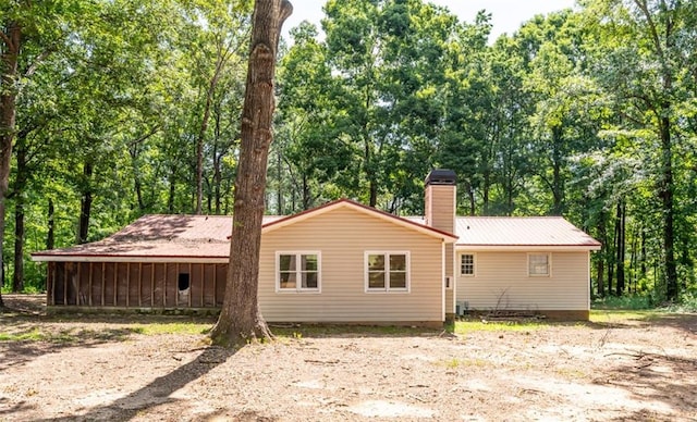 back of property featuring metal roof and a chimney