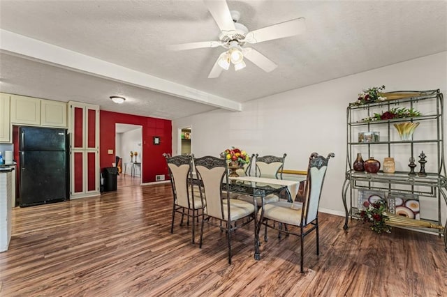 dining area with beamed ceiling, a textured ceiling, a ceiling fan, and wood finished floors