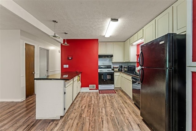 kitchen featuring dark countertops, electric range oven, freestanding refrigerator, a peninsula, and dishwashing machine