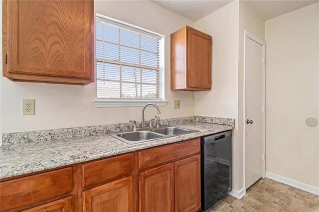 kitchen with dishwasher, light countertops, brown cabinets, and a sink