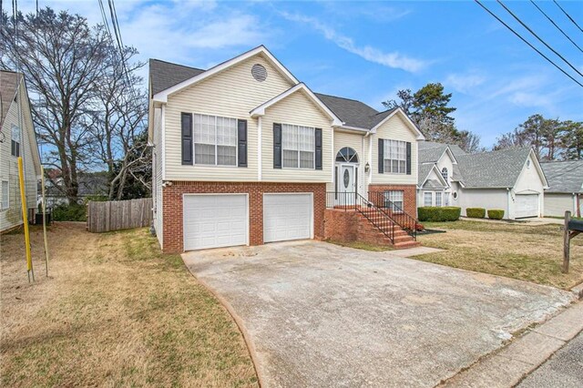 bi-level home featuring a front lawn, fence, concrete driveway, an attached garage, and brick siding