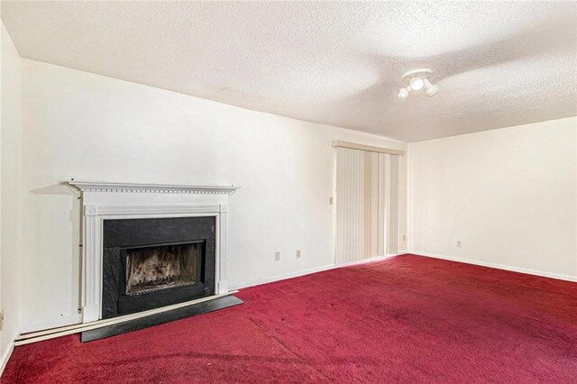 unfurnished living room featuring carpet flooring, a fireplace, a textured ceiling, and baseboards