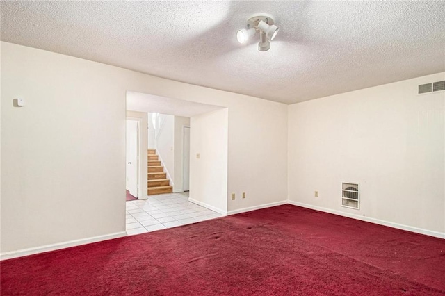empty room with visible vents, baseboards, stairway, carpet flooring, and a textured ceiling
