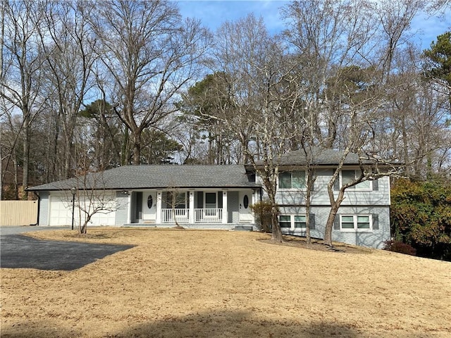 view of front of property featuring brick siding, fence, aphalt driveway, covered porch, and an attached garage
