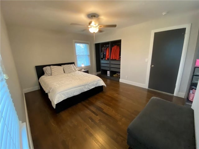 bedroom with a closet, baseboards, dark wood-type flooring, and a ceiling fan