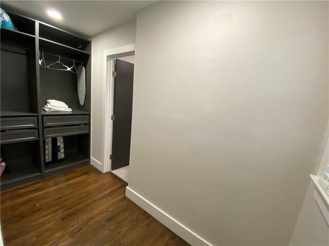 corridor with baseboards and dark wood-style flooring