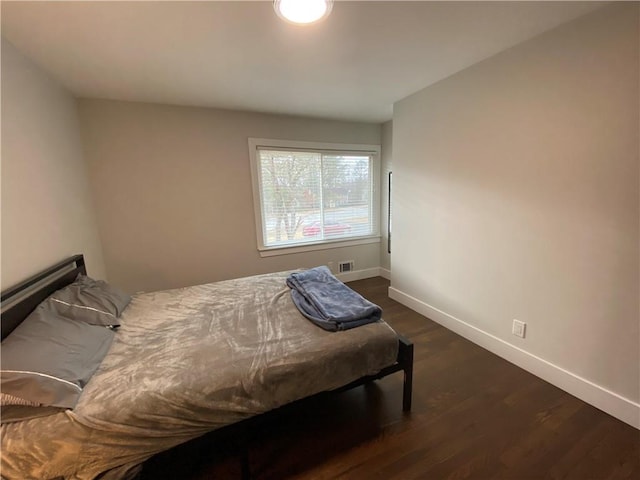 bedroom with visible vents, baseboards, and dark wood-type flooring