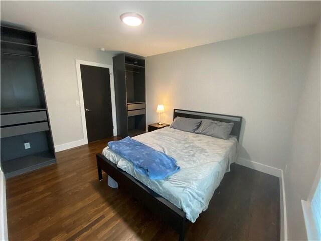bedroom with baseboards and dark wood finished floors