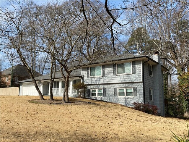 split level home featuring an attached garage, a chimney, and fence