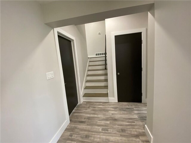 hallway featuring stairs, wood finished floors, visible vents, and baseboards