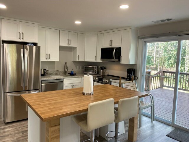 kitchen with visible vents, a sink, butcher block countertops, white cabinets, and appliances with stainless steel finishes