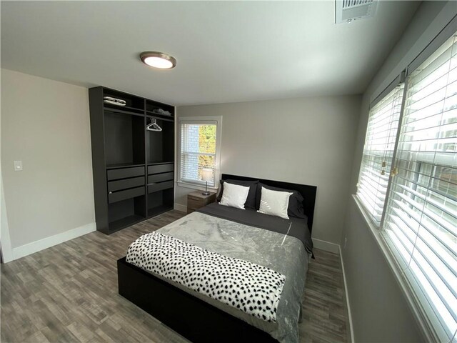 bedroom with visible vents, baseboards, and wood finished floors