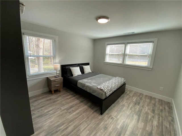 bedroom featuring visible vents, baseboards, and wood finished floors