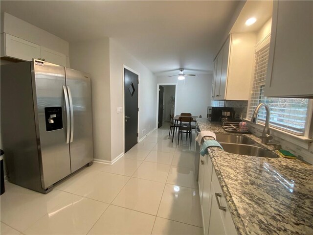 kitchen with a sink, backsplash, stainless steel fridge, light tile patterned floors, and ceiling fan