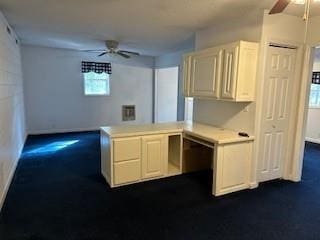 kitchen with a peninsula, light countertops, a ceiling fan, and white cabinets