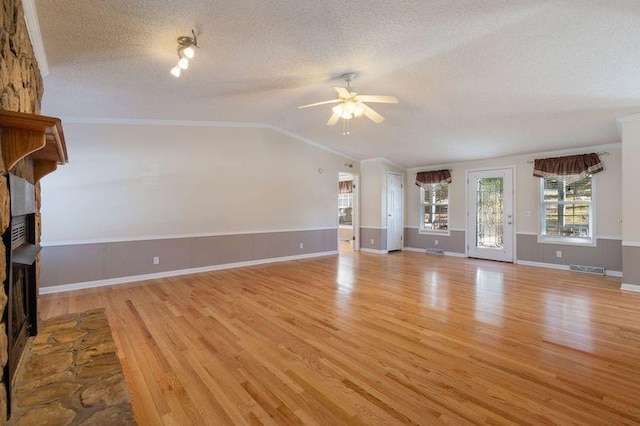 unfurnished living room featuring light hardwood / wood-style flooring, ceiling fan, a fireplace, a textured ceiling, and vaulted ceiling